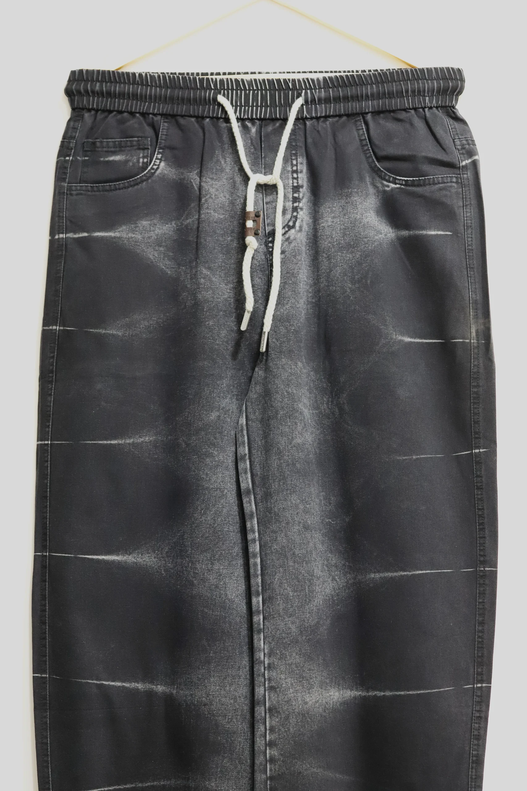 Men's black baggy jeans with vertical white side stripes paired with streetwear sneakers